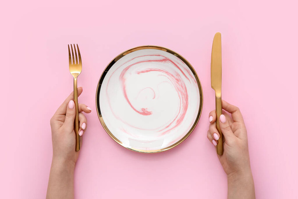 Donna con posate e piatto vuoto su sfondo rosa - Foto, immagini