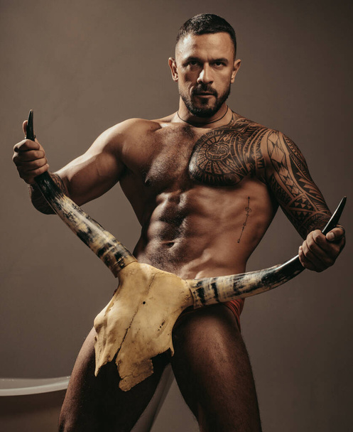 sport and fitness, health. brutal sportsman hold animal skull. steroids. muscular macho man with athletic body. sexy abs of tattoo man. male fashion. confidence charisma. nude male body. seduction. - Foto, Imagen
