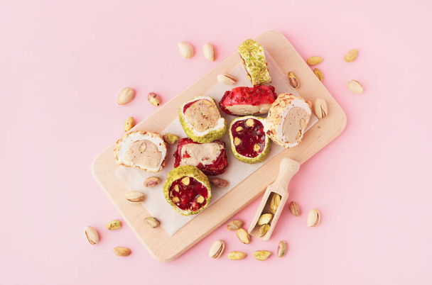 Wooden board with tasty Turkish delight on pink background - Фото, изображение