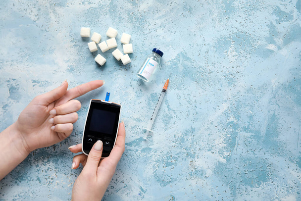Diabetic woman using digital glucometer on grunge background - Photo, image