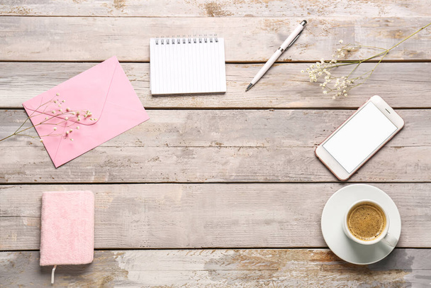 Rámeček z notebooků, obálky, mobilního telefonu a šálku kávy na ošlehaném dřevěném stole - Fotografie, Obrázek