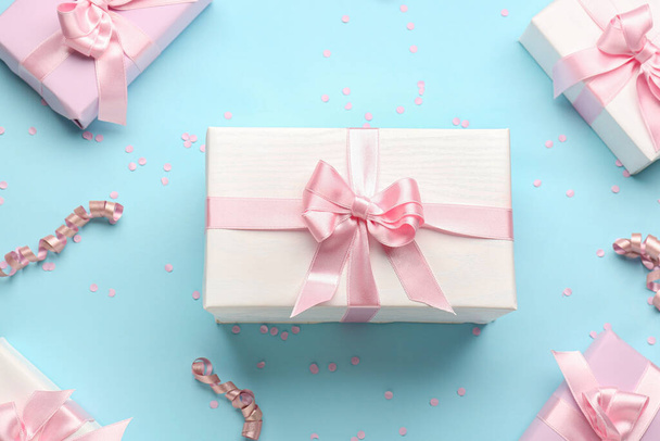 Gift boxes with beautiful bows, serpentine and confetti on blue background - Fotó, kép