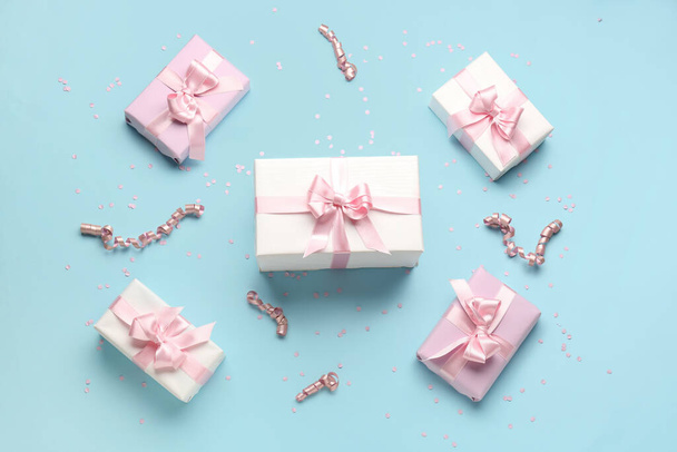 Κουτιά δώρου με όμορφα τόξα, φιόγκο και κονφετί σε μπλε φόντο - Φωτογραφία, εικόνα