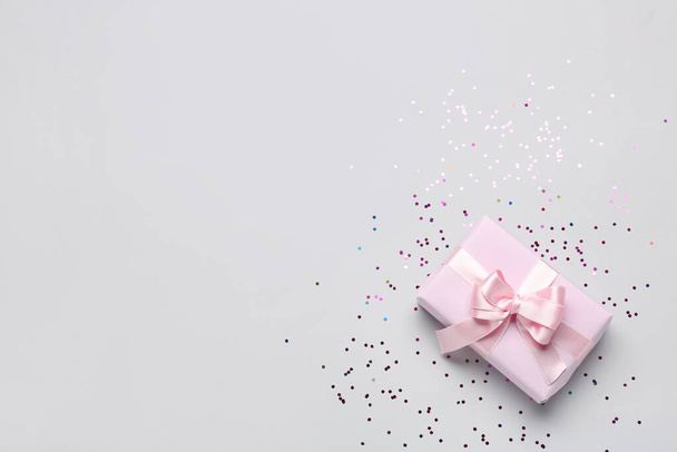 Gift box with beautiful bow and confetti on grey background - Fotografie, Obrázek
