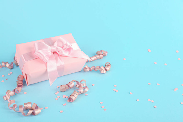 Gift box with bow, confetti and serpentine on blue background - Foto, afbeelding