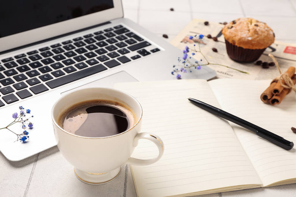 Filiżanka kawy z notatnikiem, kwiaty i laptop na białym stole, zbliżenie - Zdjęcie, obraz