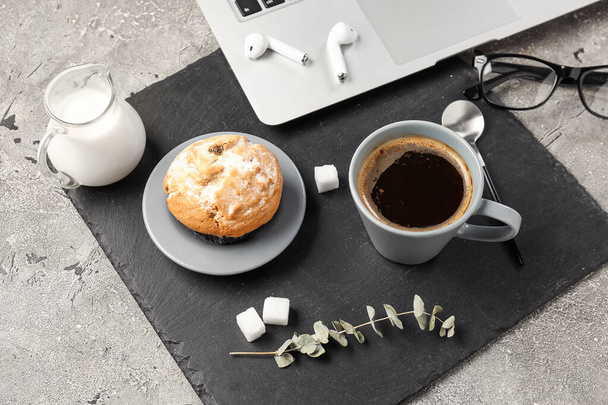 Tazza di caffè con muffin, latte, laptop e auricolari su sfondo grunge, primo piano - Foto, immagini