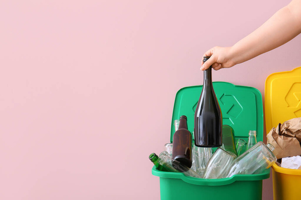 Vrouw gooit vuilnis in vuilnisbak bij roze muur. Recycling concept - Foto, afbeelding