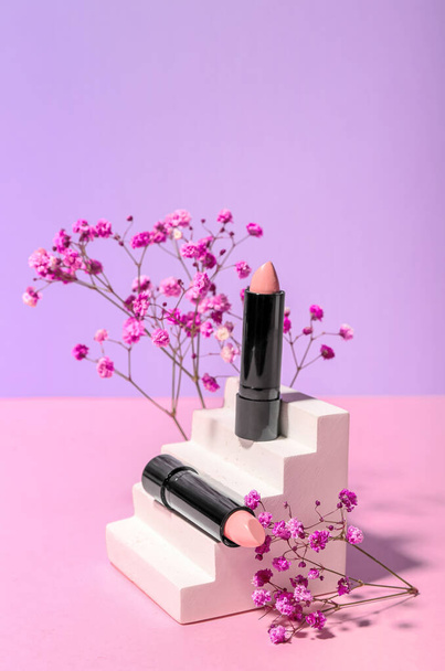 Plaster podium with lipsticks and gypsophila flowers on lilac background - Valokuva, kuva