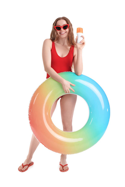Belle jeune femme avec crème solaire et anneau gonflable sur fond blanc - Photo, image