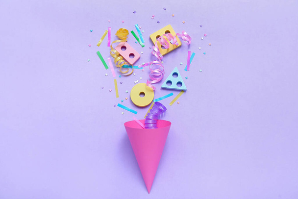 Party cone with baby blocks, confetti and serpentine on lilac background. Children's Day celebration - Φωτογραφία, εικόνα
