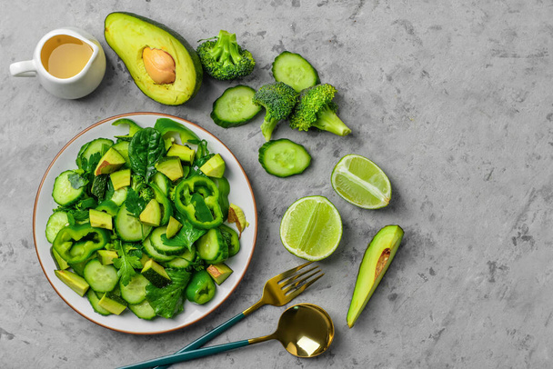 Тарелка салата с зелеными овощами и ингредиентами на сером фоне гранжа - Фото, изображение