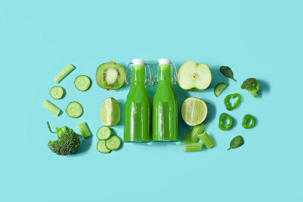 Glasflaschen mit leckerem grünen Saft und Zutaten auf türkisfarbenem Hintergrund - Foto, Bild