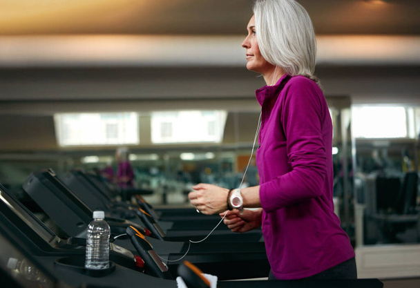 Часы несколько миль на беговой дорожке. взрослая женщина, упражняющаяся на беговой дорожке в спортзале - Фото, изображение