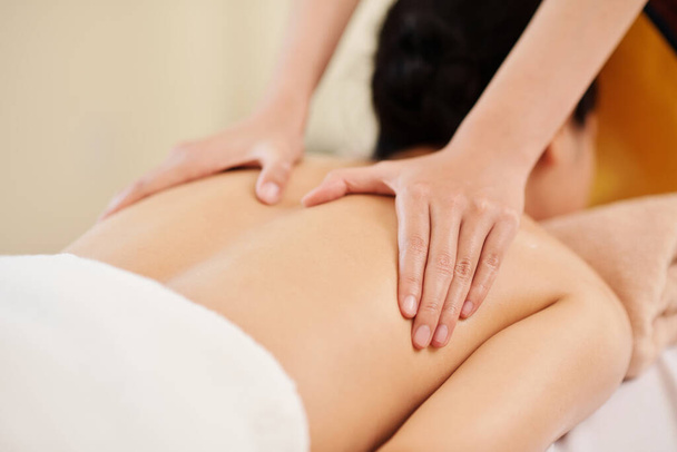 Ręce masażystki głaskającej kobiecą klientkę, aby rozgrzać mięśnie - Zdjęcie, obraz