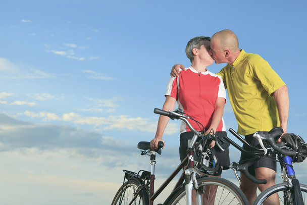 Ένας ανώτερος άνθρωπος και μια γυναίκα με ποδήλατο κατά το ηλιοβασίλεμα. - Φωτογραφία, εικόνα