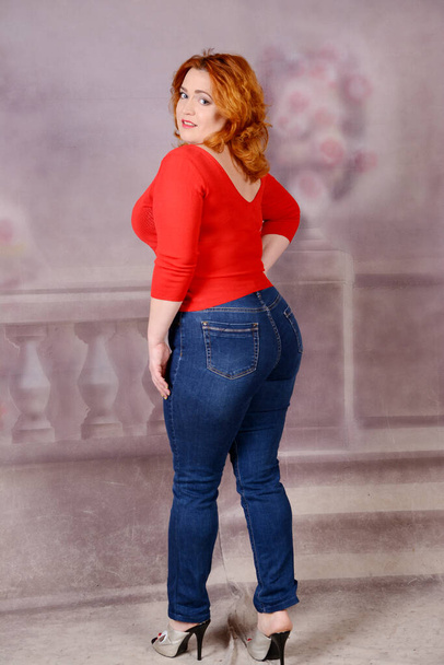 woman turned her back to the camera big puffy breasts and ass redhead beauty in high heels Woman with red jacket standing on bakground. High quality photo - Fotó, kép