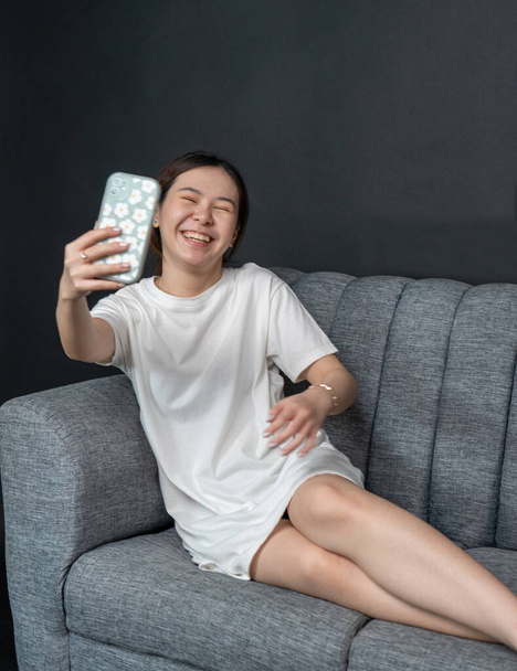 Retrato de fotografía de una mujer asiática tomando una selfie en un cómodo sofá, camisa vestido maqueta plantilla imagen - Foto, imagen