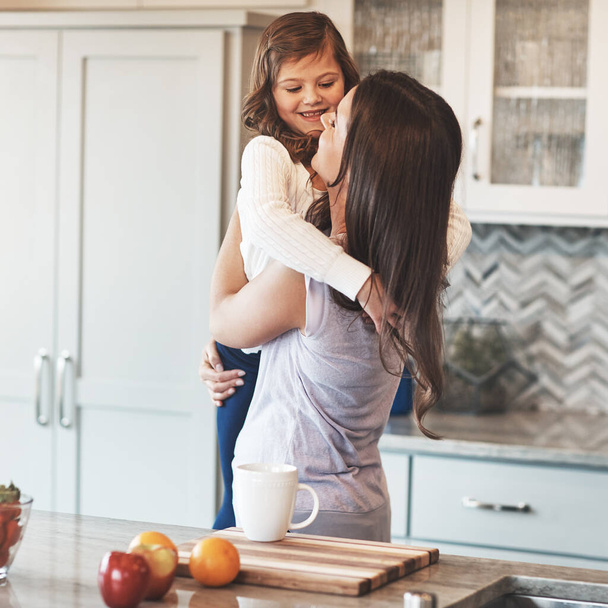 Estas armas fueron hechas para abrazar. una madre feliz abrazando a su linda niña en la cocina en casa - Foto, Imagen