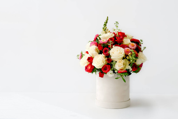 Beautiful bouquet of flowers decorated in round box on light background - Фото, изображение
