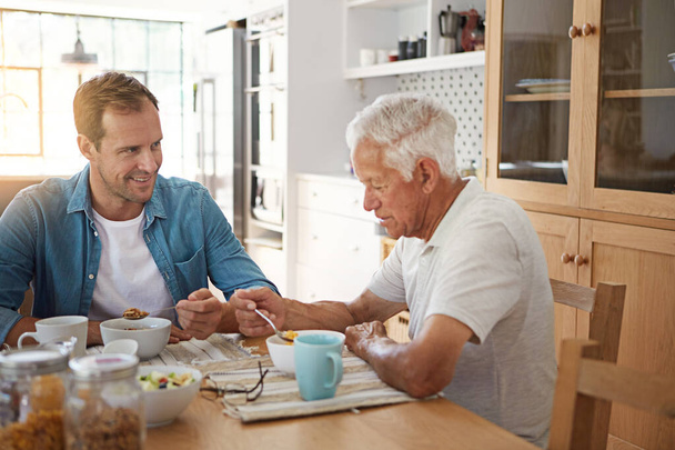 Nigdy nie tracą szansy na więź. mężczyzna jedzący śniadanie ze starszym ojcem w kuchni w domu - Zdjęcie, obraz