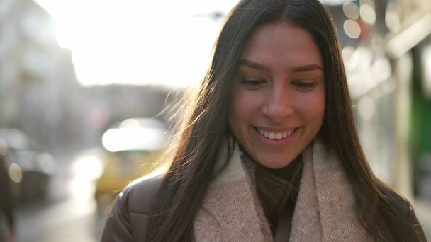 Portrait d'une jeune femme heureuse marchant vers la caméra à l'extérieur dans la rue de la ville. Gros plan d'une fille adulte du Moyen-Orient dans les années 20 souriant sur le trottoir - Photo, image