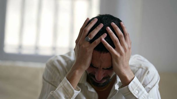 Ein besorgter junger Mann kämpft zu Hause mit psychischen Problemen, fühlt sich überfordert und hilflos - Foto, Bild