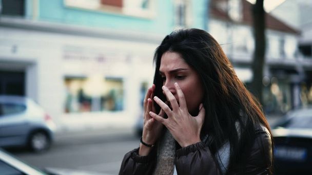 Worried young woman walks in street shaking head in disbelief. Preoccupied female person in 20s feeling frustration and stress during difficult times - Фото, изображение