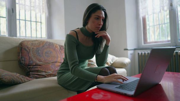 One concentrated Arab adult girl in front of laptop computer surfing the internet. A Middle Eastern young woman using modern technology - Zdjęcie, obraz