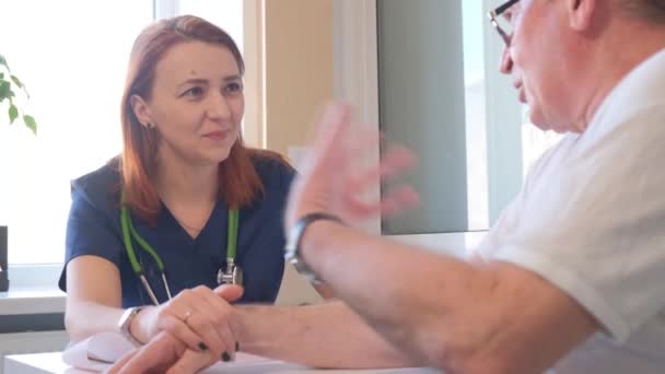 Médica sorridente conforta paciente segurando a mão. Cuidados e compaixão do médico na clínica. 4k vídeo - Filmagem, Vídeo