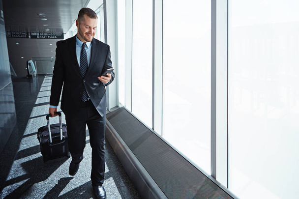 Κάνοντας καλή χρήση του wifi αεροδρόμιο. εκτελεστικός επιχειρηματίας που διασχίζει ένα αεροδρόμιο κατά τη διάρκεια επαγγελματικού ταξιδιού - Φωτογραφία, εικόνα