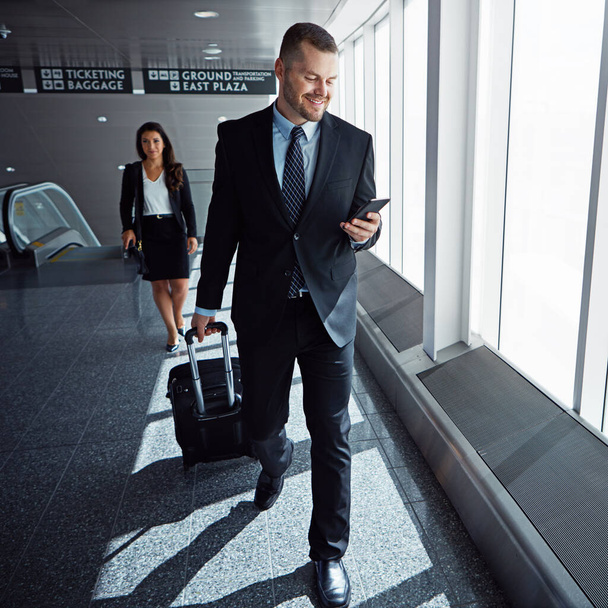 Τώρα μπορεί να συνδεθεί, όποτε θέλει. δύο εκτελεστικοί επιχειρηματίες που περπατούν σε ένα αεροδρόμιο κατά τη διάρκεια επαγγελματικού ταξιδιού - Φωτογραφία, εικόνα