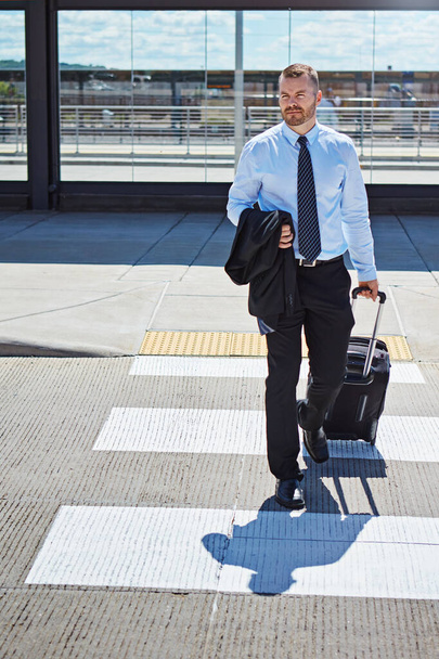 A carreira dele está prestes a arrancar. um empresário profissional caminhando em direção a um aeroporto com sua bagagem - Foto, Imagem