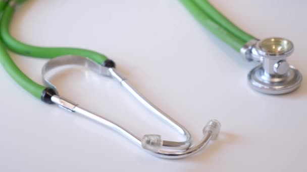 Stethoscope az asztalon a klinikán. Zöld sztetoszkóp. Egészségügyi ellátás. 4k videó - Felvétel, videó