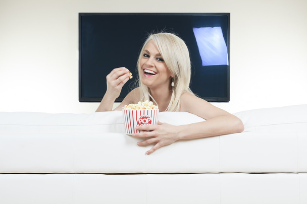 Fröhliche Frau isst Popcorn, während sie sich einen Film im Fernsehen ansieht - Foto, Bild