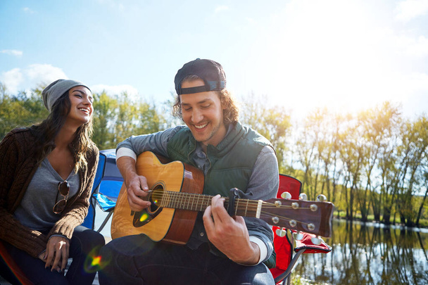 Nada mejor que tener un dulce musicalmente inclinado a tu lado. un joven tocando a su novia una canción en su guitarra - Foto, imagen