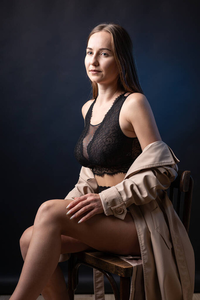 Studio portrait of a young slender girl in lingerie against a black background. - Foto, imagen