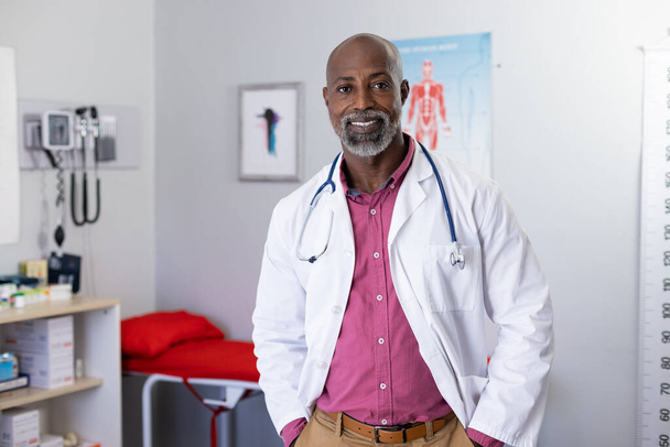 Portrait of happy african american male doctor wearing stethoscope and smiling at doctor's office. Hospital, medicine and healthcare. - Foto, Bild