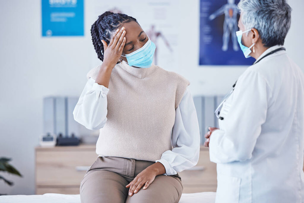 Consultation, doctor and patient with face mask, headache and covid healthcare advice at clinic. Black woman consulting medical professional, health care check and faq, pain info and help at hospital. - Foto, Imagen