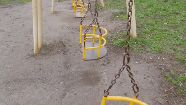 Kinderschaukeln mit Holzsitzen an Ketten auf Spielplatz aufgehängt - Filmmaterial, Video