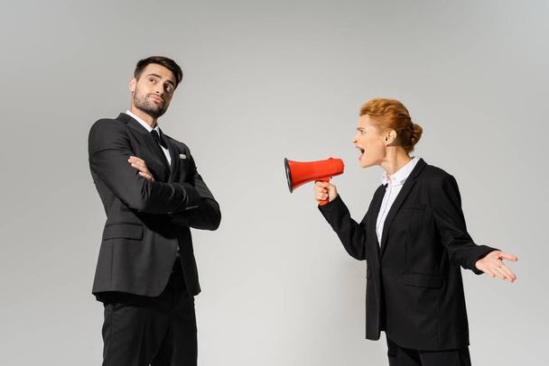 irritated businesswoman shouting at calm and confident manager standing with folded arms isolated on grey - Foto, Imagem