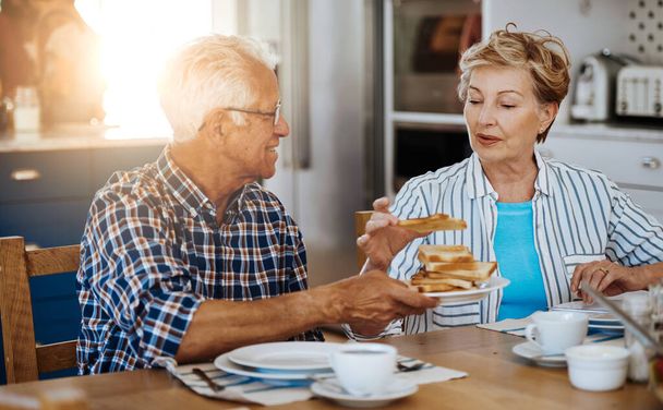 More toast for you, my dear. a senior couple having breakfast together at home - 写真・画像