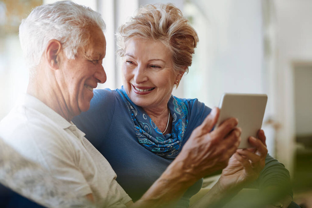 Befähigt, sich mit den Dingen zu verbinden, die wichtig sind. ein glückliches Seniorenpaar mit einem digitalen Tablet zusammen auf dem heimischen Sofa - Foto, Bild