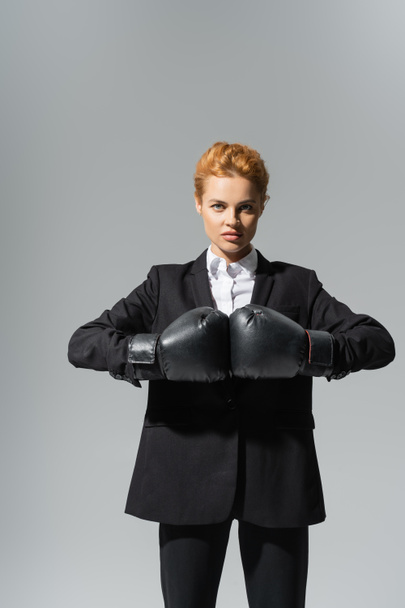 determined businesswoman in boxing gloves and black formal wear isolated on grey - Foto, imagen