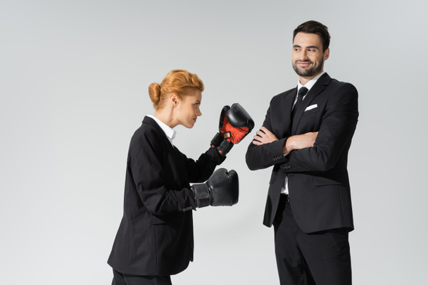 ruiva mulher em uso formal de boxe perto de empresário alegre de pé com braços cruzados isolados em cinza - Foto, Imagem