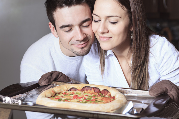 A Happy young couple eating pizza at the kitchen - Foto, imagen