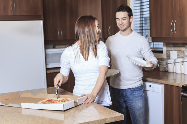 A Happy young couple eating pizza at the kitchen - Foto, imagen