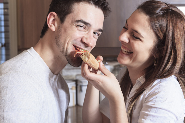 A Happy young couple eating pizza at the kitchen - Photo, Image