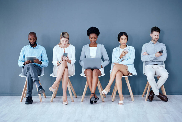 Business people, networking and technology in waiting room for interview, meeting or job search at office. Diversity group of employees sitting in row for recruitment process, collaboration or hiring. - Foto, imagen