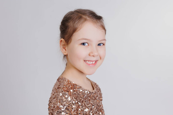 Smiling cute little girl in golden dress in studio - Fotoğraf, Görsel